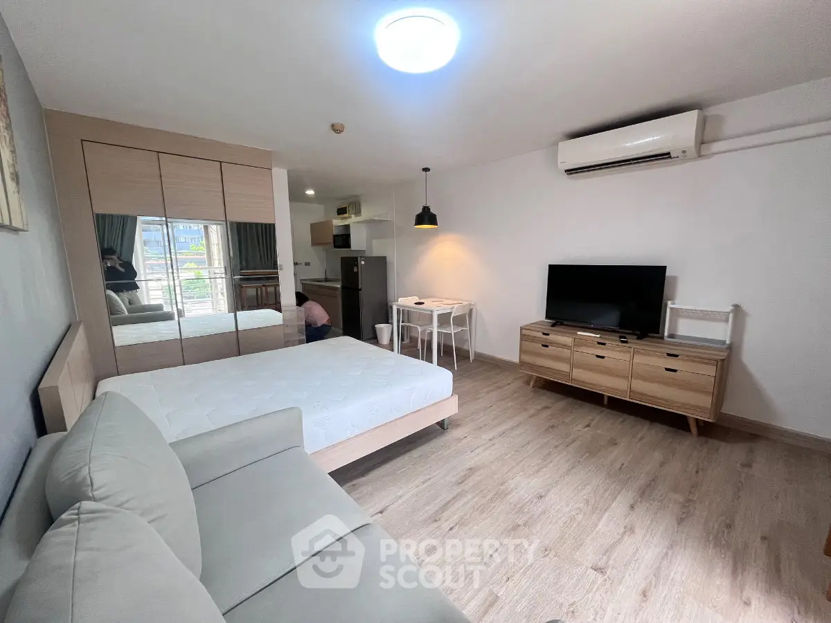 Modern studio apartment with cozy living area, bed, and kitchenette, featuring stylish decor and ample natural light.