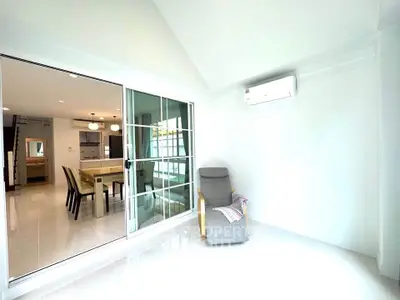 Bright living area with sliding glass doors leading to modern dining and kitchen space.