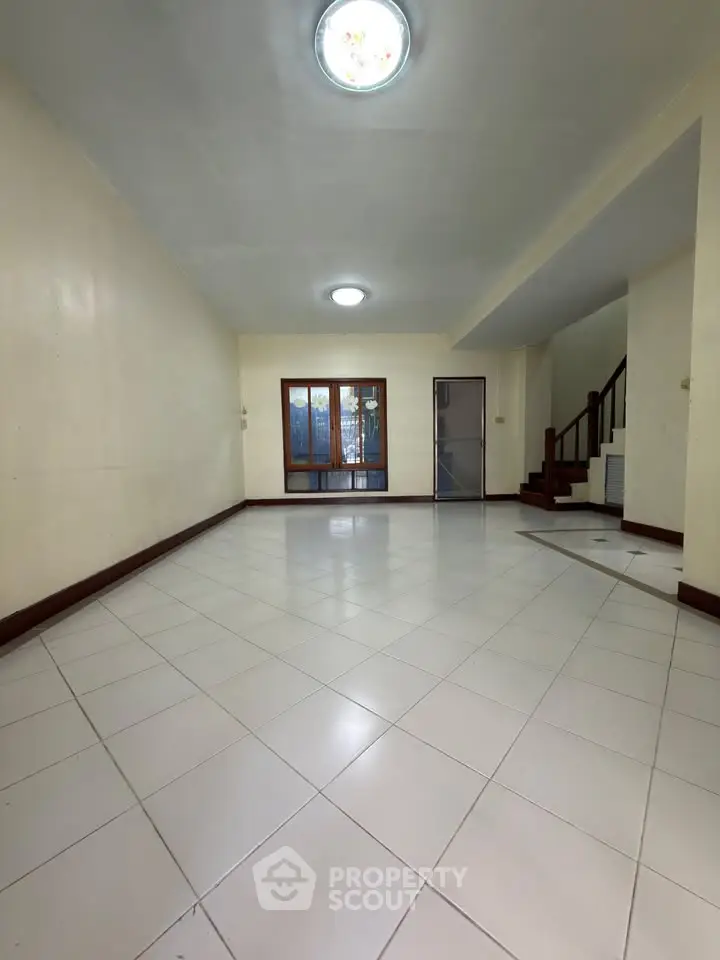 Spacious living room with tiled floor and staircase in modern home