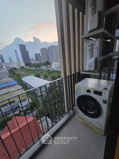 High-rise balcony with washing machine and stunning city skyline view at sunset.