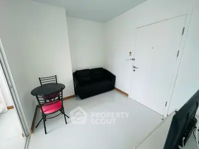 Cozy minimalist living room with black sofa and small dining table, perfect for compact spaces.