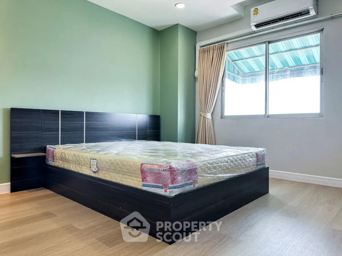 Modern bedroom with large window and stylish bed frame in a cozy apartment.