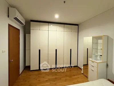 Spacious bedroom with modern wardrobe and wooden flooring in a stylish apartment.