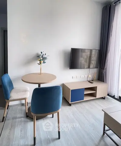 Modern living room with stylish furniture and wall-mounted TV, featuring natural light and elegant decor.