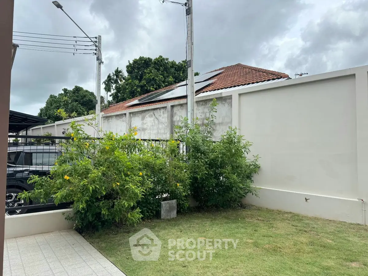 Charming garden view with lush greenery and modern fence in suburban setting.