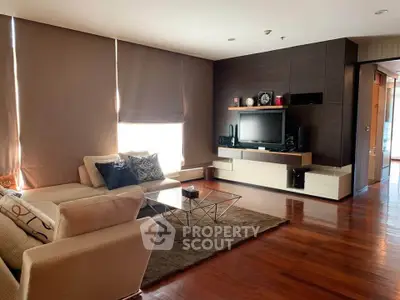 Spacious modern living room with elegant decor and hardwood floors, featuring a cozy sofa and entertainment center.