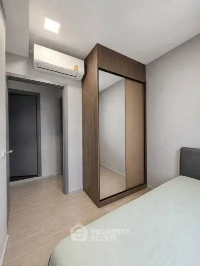 Modern bedroom with sleek wardrobe and air conditioning unit, perfect for comfortable living.