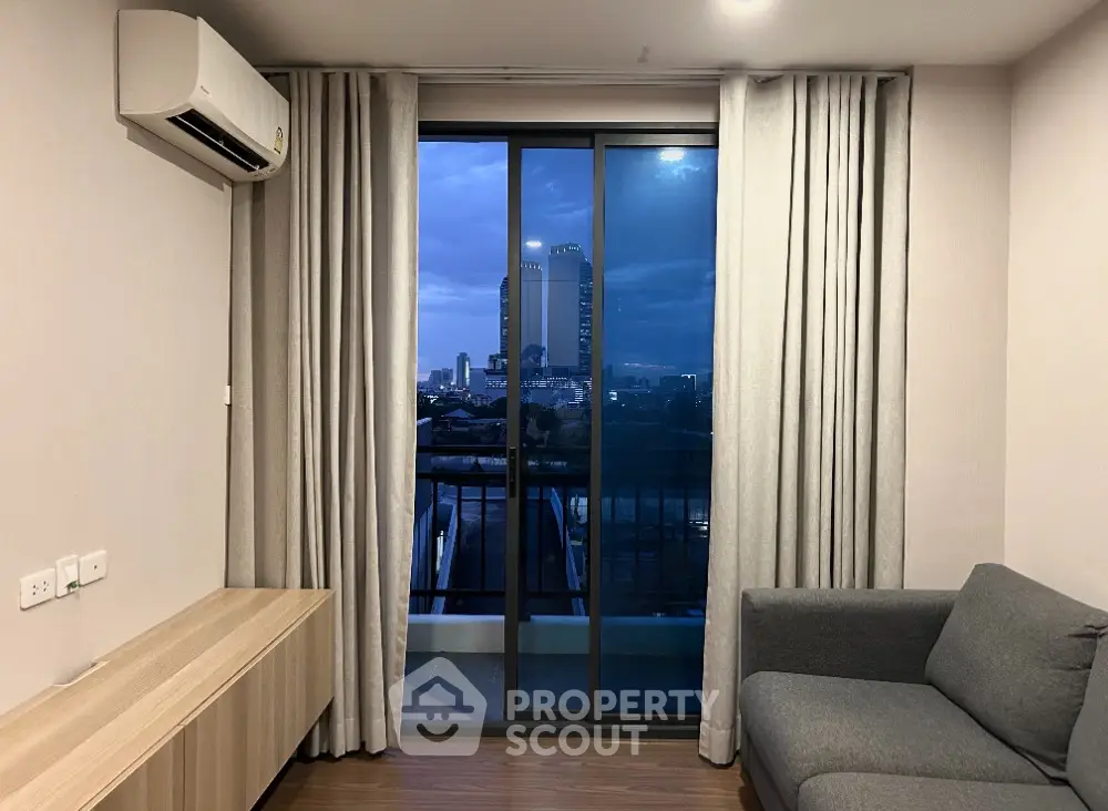Modern living room with city view from balcony, featuring sleek furniture and large windows.