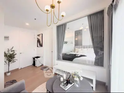 Modern living room with elegant decor and view into stylish bedroom through glass partition.