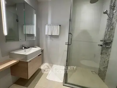 Modern bathroom with glass shower and sleek vanity in contemporary apartment.