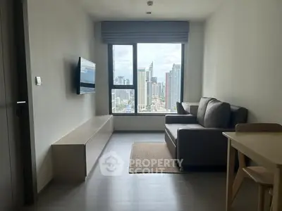 Modern living room with city view, featuring sleek furniture and large window.