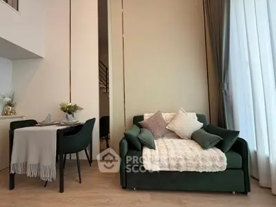 Modern living room with elegant green sofa and dining area, featuring floor-to-ceiling windows and stylish decor.