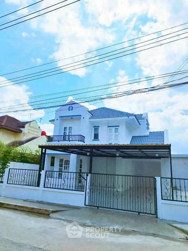 Charming two-story white house with gated driveway and blue sky backdrop.