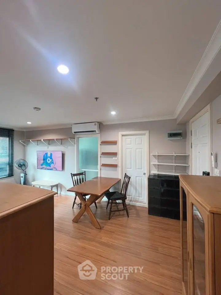 Spacious dining area with wooden flooring and modern furniture in a cozy apartment.