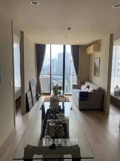Modern living room with city view, elegant decor, and natural light in a high-rise apartment.