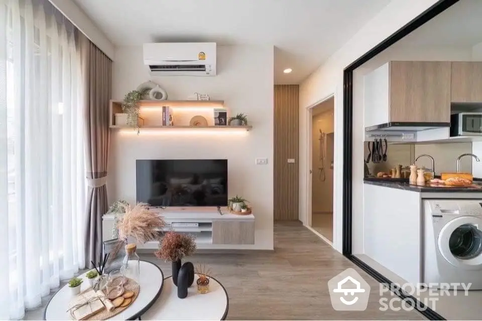 Modern studio apartment with integrated living space, featuring a sleek kitchen with high-end appliances, cozy living area, and a washing machine.