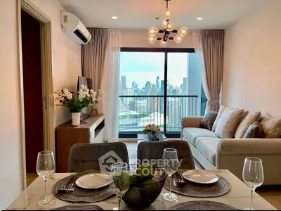 Stylish living room with city view, modern decor, and elegant dining setup in a high-rise apartment.