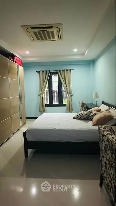 Spacious bedroom with modern decor and large window for natural light