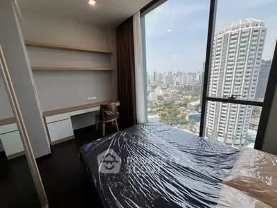 Modern bedroom with city view and sleek furnishings in high-rise apartment.