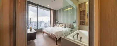 Luxurious bedroom with stunning city view and modern bathtub in high-rise apartment.