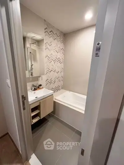 Modern bathroom with stylish chevron tiles and built-in bathtub in a contemporary apartment.