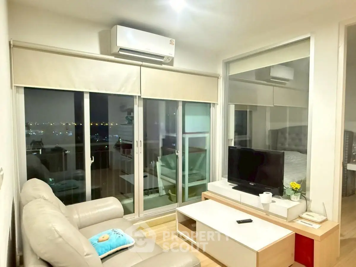 Modern living room with city view, featuring cozy sofa, TV, and large windows for natural light.