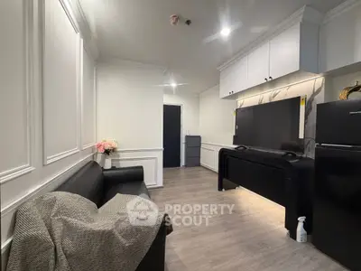 Modern living room with sleek black sofa, stylish cabinetry, and elegant decor in a contemporary apartment.