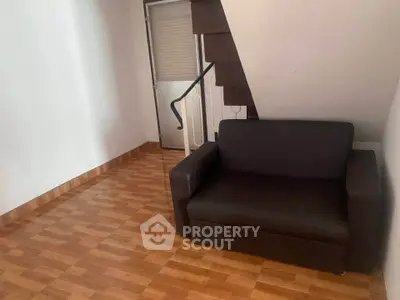 Cozy living room with modern brown sofa and wooden flooring under staircase.