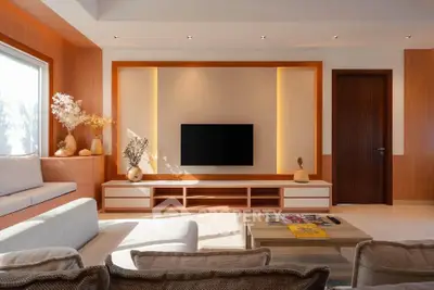 Modern living room with elegant wooden accents and built-in TV unit, featuring cozy seating and natural light.