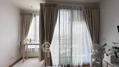 Bright bedroom with large windows and city view, featuring elegant curtains and cozy decor.