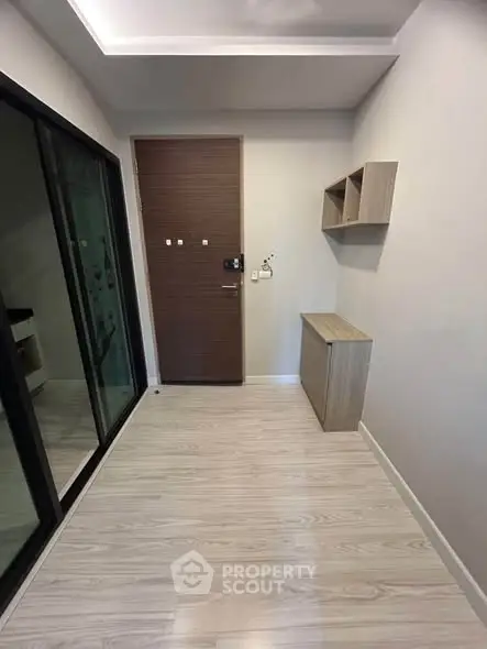 Modern apartment entrance with sleek wooden flooring and storage solutions.