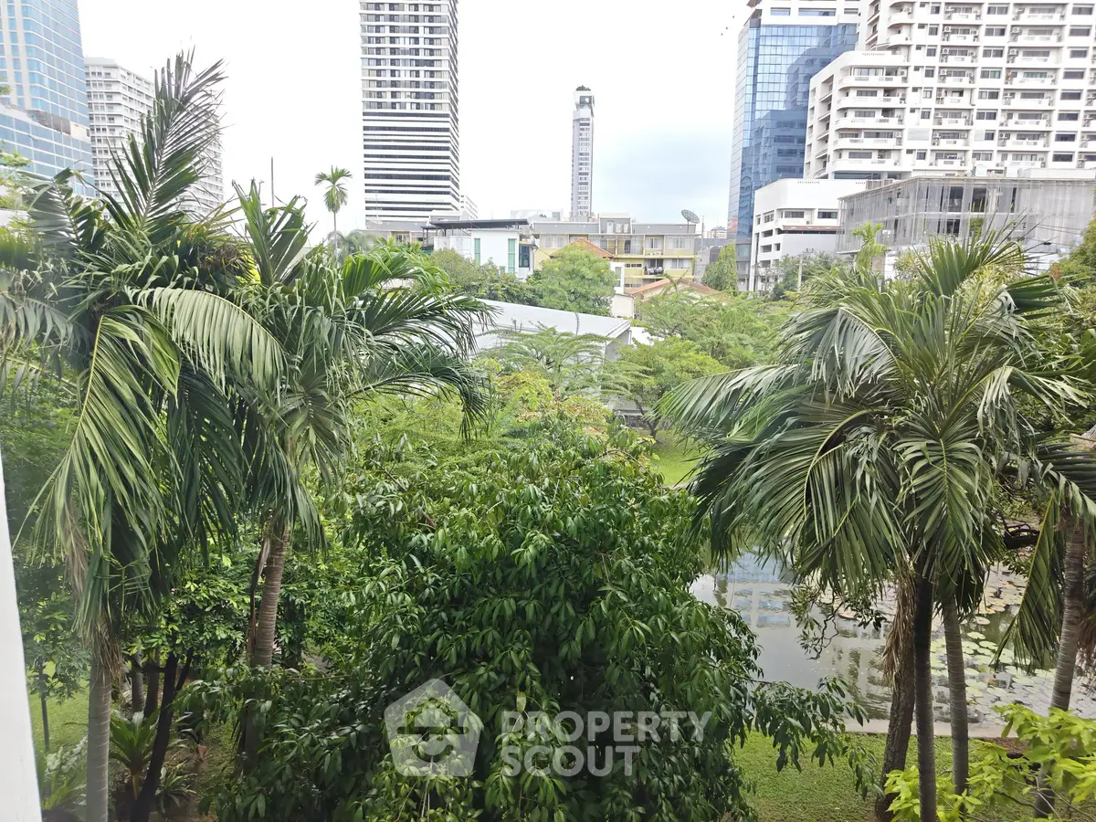 Lush garden view with palm trees and city skyline in the background, perfect for urban nature lovers.