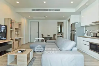 Modern open-layout living room with sleek kitchen and cozy seating area, perfect for contemporary living.