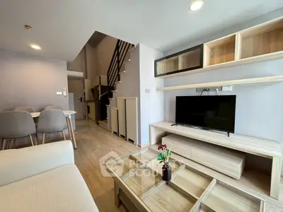 Modern living room with stylish furniture and open layout, featuring a cozy dining area and sleek staircase.