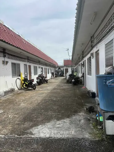 Charming residential alley with white buildings and red roofs, featuring motorbikes parked along the pathway.