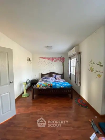 Spacious bedroom with wooden flooring and charming wall decor