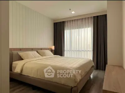 Spacious bedroom with modern decor and large window for natural light.