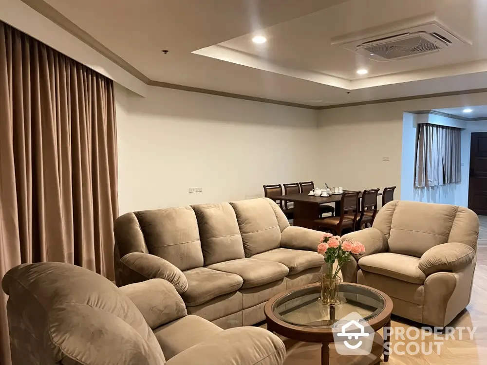 Spacious living room with plush seating and elegant dining area in the background, perfect for entertaining and relaxation.