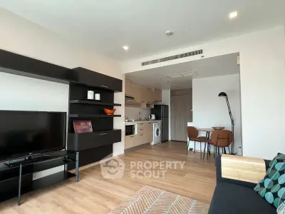 Modern open-plan living room with sleek kitchen and dining area, featuring stylish furniture and wooden flooring.