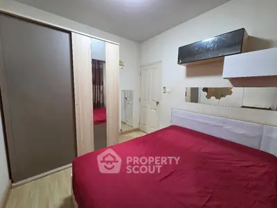 Cozy bedroom with red bedding and modern wardrobe in stylish apartment.