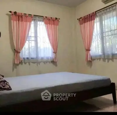 Cozy bedroom with natural light and pink curtains, perfect for relaxation.