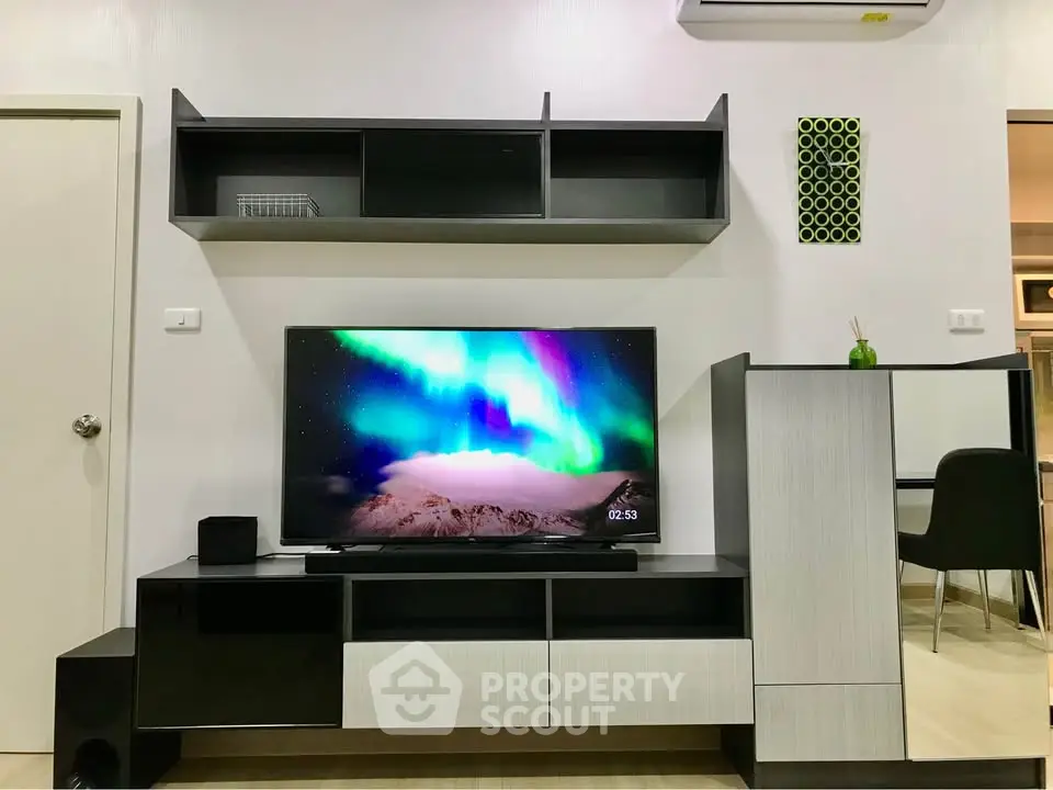 Modern living room with sleek TV unit and wall shelves, showcasing stylish interior design.