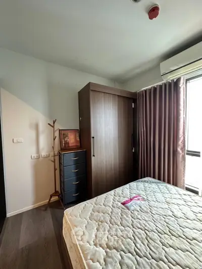 Cozy bedroom with natural light, featuring a wooden wardrobe and modern furnishings.