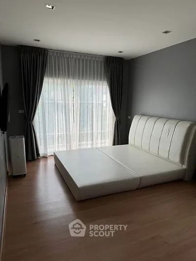 Spacious bedroom with modern minimalist design and large window for natural light.