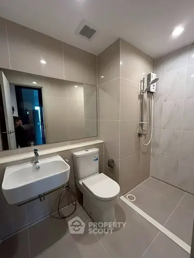 Modern bathroom with sleek fixtures and spacious shower area in a contemporary apartment.