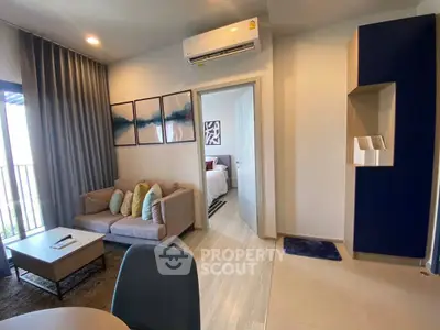 Modern living room with cozy sofa, air conditioning, and stylish decor leading to a bedroom.