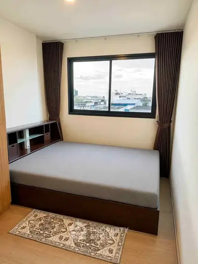 Cozy bedroom with large window and modern furnishings, offering a serene view and ample natural light.