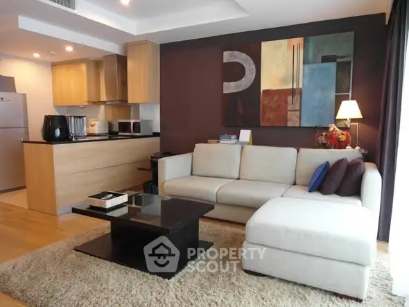 Modern living room with open kitchen, stylish decor, and cozy seating area in a contemporary apartment.