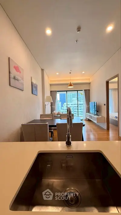 Modern open-plan living room with city view, featuring sleek kitchen sink and elegant decor.