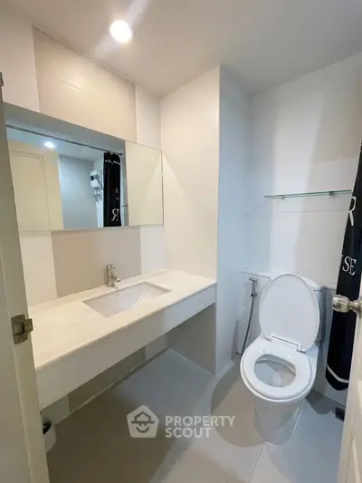Modern bathroom with sleek white fixtures and large mirror